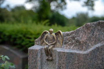 Kleiner Engel sitzt auf dem Grabstein  © Blende8