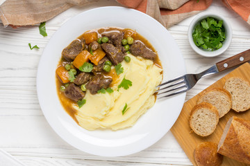 Beef stew, pumpkin and green peas with mashed potatoes.  Delicious homemade dinner. Autumn food