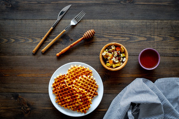 Traditional belgian waffles with dried fruit, nuts and caramel on dark wooden background flat lay copy space
