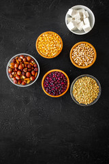 Products rich protein. Legumes, nuts, low-fat cheese. Raw beans, chickpeas, lentil, almond, hazelnut on black background top view copy space