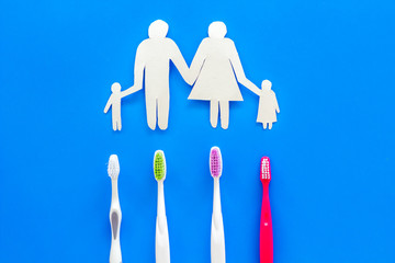 Teeth care, dental care. Set of toothbrushes near family silhouette on blue background top view copy space