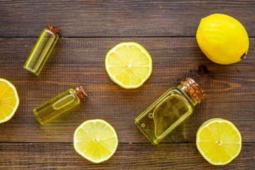 Obraz na płótnie Canvas Natural cosmetics. Lemon essential oil near halfs os lemons on dark wooden background top view closeup
