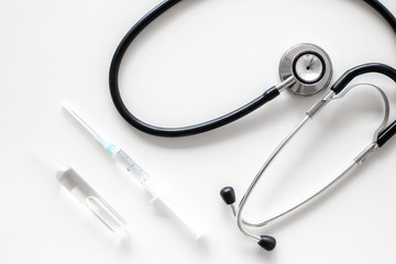 Infuenza vaccine in syringe near stethoscope on white background top view