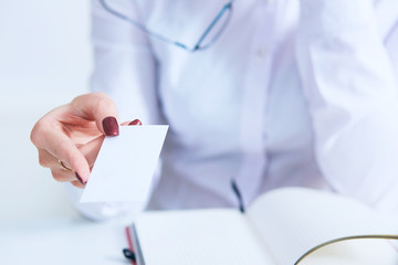 Female physician hand give white blank calling card to businesswoman closeup in office.