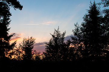 A sunset is the sun&rsquo;s fiery kiss to the night, two white lines from flying planes