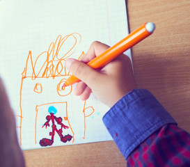 Boy is painting a picture. A beautiful child with felt-tip pens sits at the table and is engaged in creativity and art. Drawing in kindergarten, school.