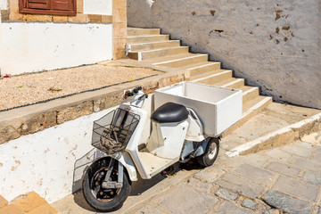 Typical Greek scooter parked on narrow street of Lindos. Rhodes island, Greece © vivoo