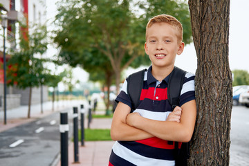 Naklejka premium Happy smiling school boy with backpack outdoors. Childhood, leisure, school and people concept