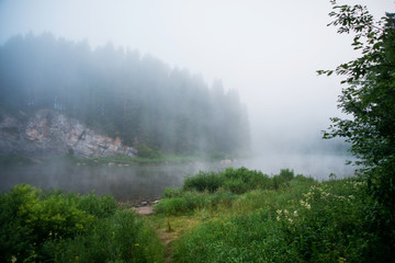 Natural background, landscape: morning fog on the river in the forest, at dawn on a summer day. Soft focus.