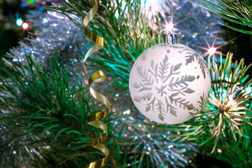 Big glass bowl with a pattern of snowflakes. Christmas toys on the Christmas tree. New Year decoration. Serpentine and lights of garlands on the Christmas tree.