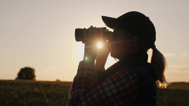Silhouette of a woman looking forward through binoculars. Search for the horizon, travel and safari concept