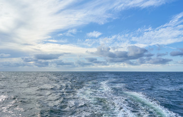 Fototapeta na wymiar Wake after cruise ship, water spray and beautiful blue sky. 