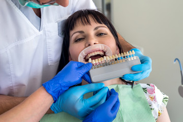 Woman in dentistry with teeth swatch sitting in chair