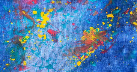 Texture of denim or colorful paint on blue jeans background. Drops of color paint on blue...