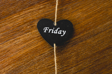 Black wooden heart with day of the week written on it, Friday