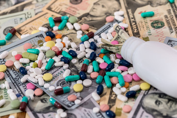 Colourful pills on dollar banknotes with container