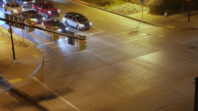 A high angle night time lapse view of traffic passing through an intersection in a large city.  	