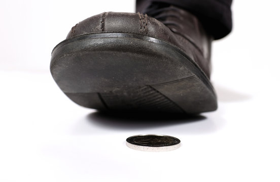 Ein Mann tritt verstohlen auf eine auf dem Boden liegende Münze