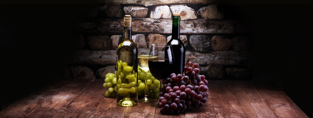 Red Wine bottle and white wine with grapes and glasses on wooden background - obrazy, fototapety, plakaty