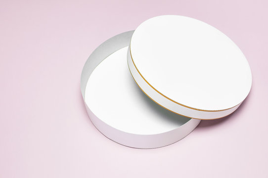 Round white cardboard blank box top view flat lay. Mock up on pink background. Packaging design, an empty box for shopping.