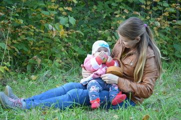 Young mother and her toddler girl having fun in autumn