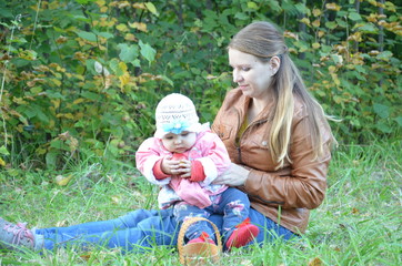 Young mother and her toddler girl having fun in autumn