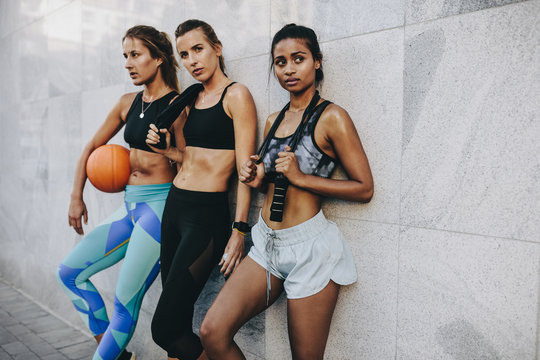 Fitness women standing outdoors after workout carrying basketbal