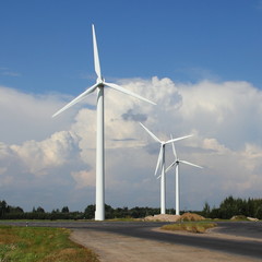 Fototapeta premium Modern power wind farm in summer against blue sky with white clouds