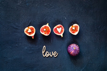 Fresh figs. Vegetarian food, concept of natural products. Creative layout of the whole and sliced figs on dark blue background with the inscription love and hearts.  Flat lay. Copy space, closeup.