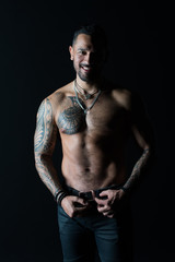 Fototapeta na wymiar Happy man with tattoo design on skin. Bearded man shirtless with fit torso. Fashion model buckle leather belt in jeans. Sportsman smile with six pack and ab. Fitness with sport and bodycare