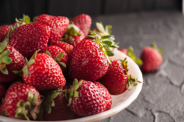 Fresh strawberries in a plate on a black background.