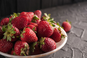 Fresh strawberries in a plate on a black background.