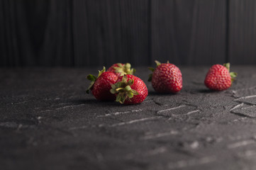 Fresh strawberries in a plate on a black background.