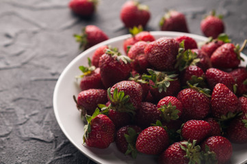 Fresh strawberries in a plate on a black background.