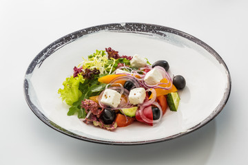 Greek salad in a plate isolated on a white background