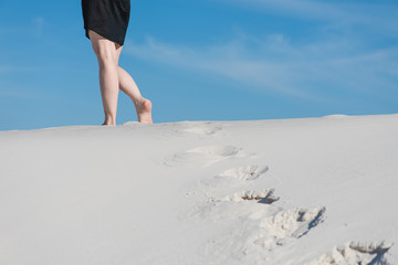 Female legs and prints on white sand