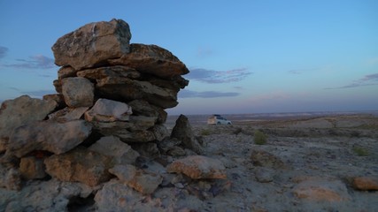 cars drive through the desert past the stones