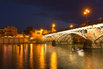 Fototapeta na wymiar Seville in Spain. Waterfront night view of the old town and historical bridge
