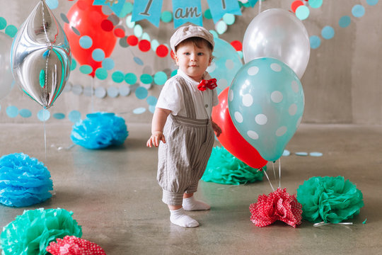 Cute baby boy first birthday party decorated with garland and balloons. Minimal studio photo