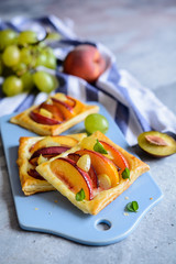 Fruit puff pastry pies with peach, plums and grapes