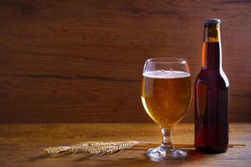 Glass and bottle of beer, ears of barley on wooden background. Ale. horizontal with copy space