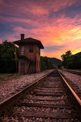 Fototapeta na wymiar Summer sunset over old control tower and train tracks