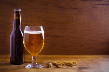 Glass and bottle of beer, ears of barley on wooden background. Ale. horizontal with copy space