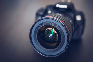 Digital camera or DSLR with camera lens with lense reflections. Photo Camera or Video lens close-up on black background DSLR objective