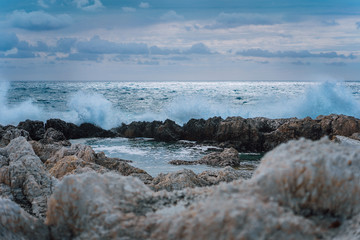 Waves splashing against rocky coastline and building natural pools. Dramatic cloudscape