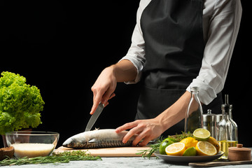 Slicing fish by the chef on a black background
