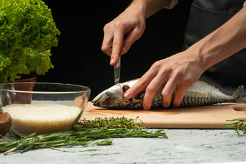 Slicing fish by the chef on a black background