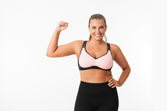 Pretty smiling plump girl in sporty top and leggings happily looking in camera over white background isolated. Plus size model