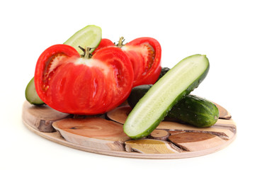 Tomatoes and cucumbers on a wooden board.