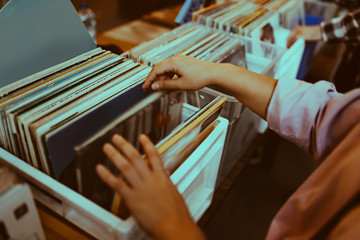 Woman is choosing a vinyl record in a musical store
